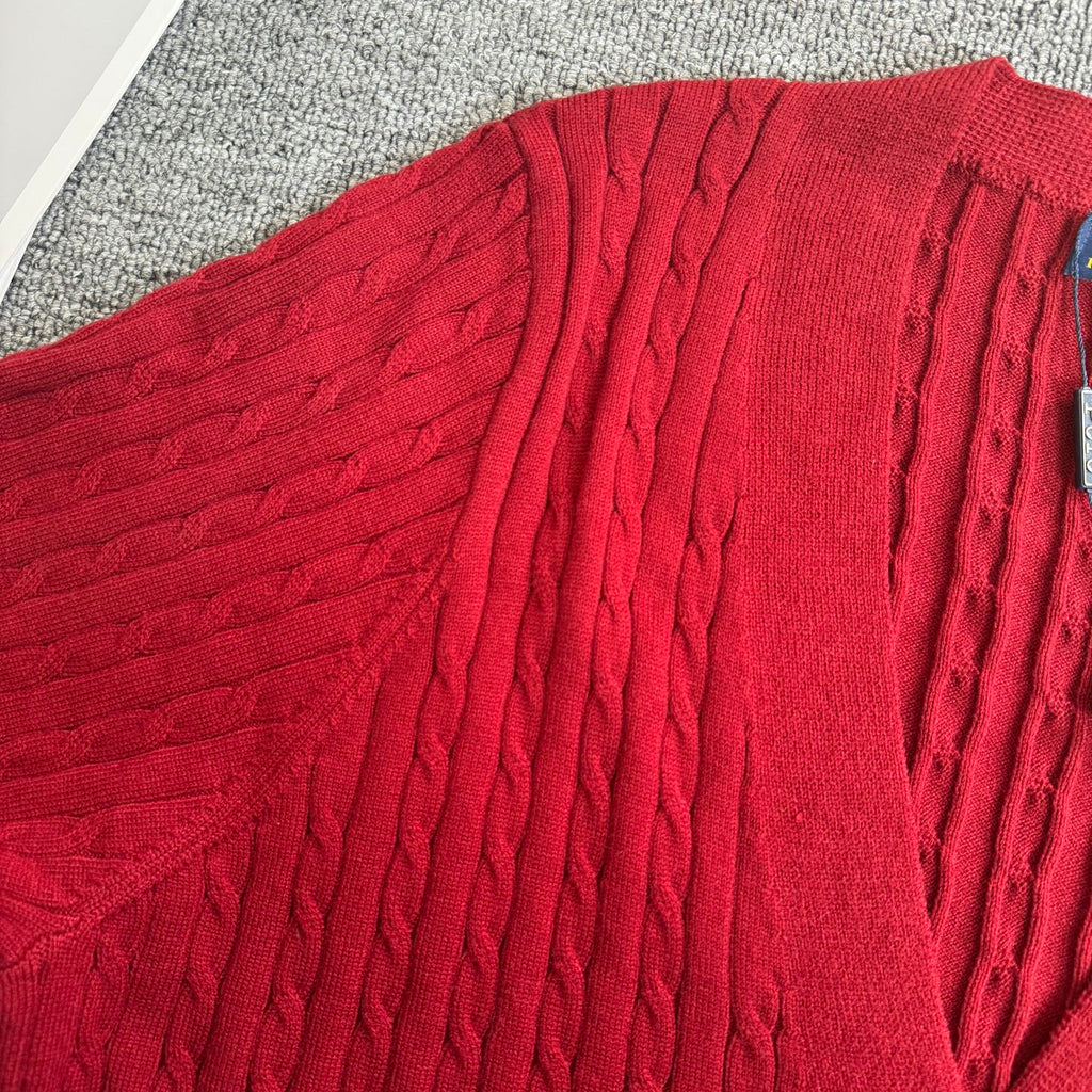 Red cable-knit cardigan fabric close-up with textured vertical cable pattern