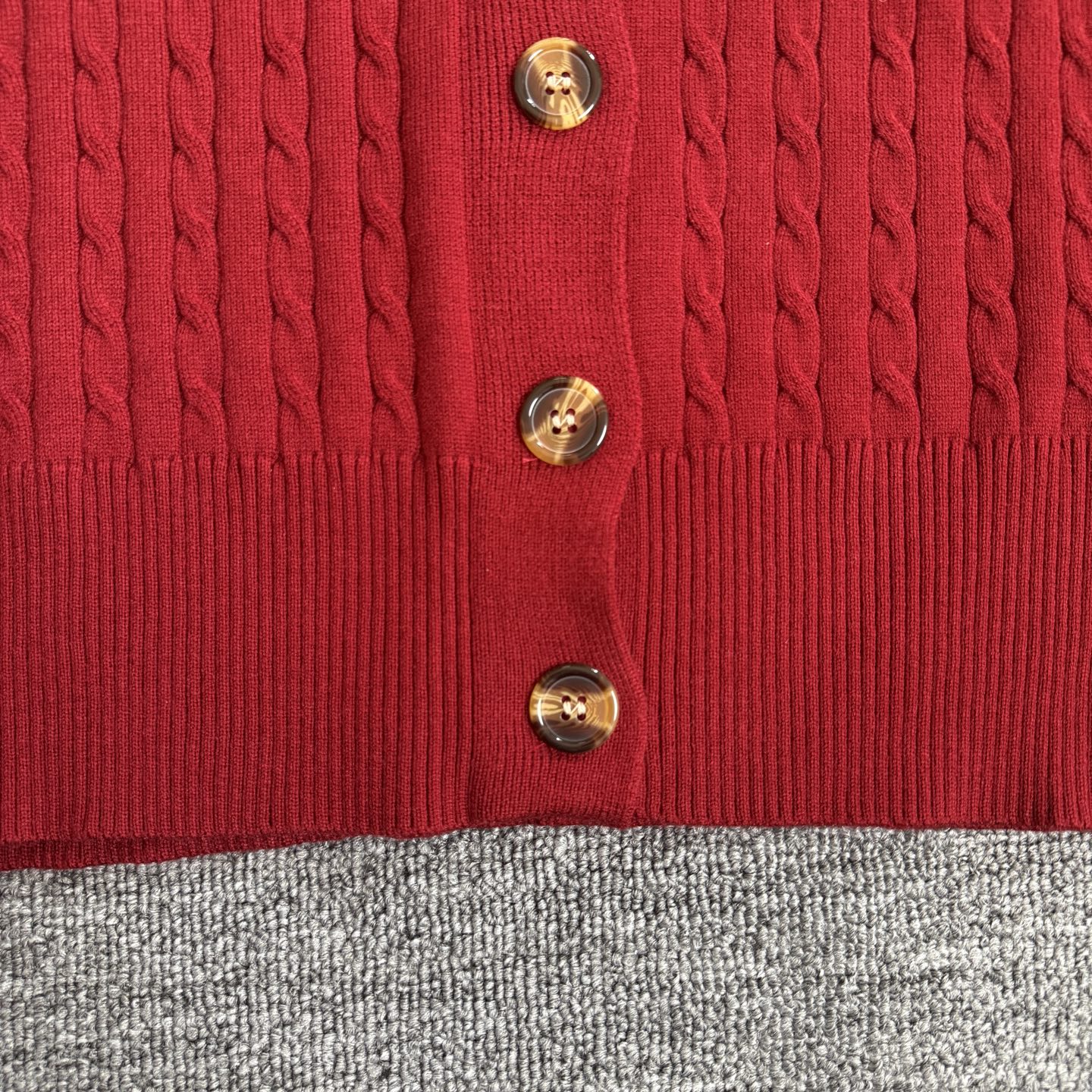 Red cable-knit cardigan front with gold tone button details