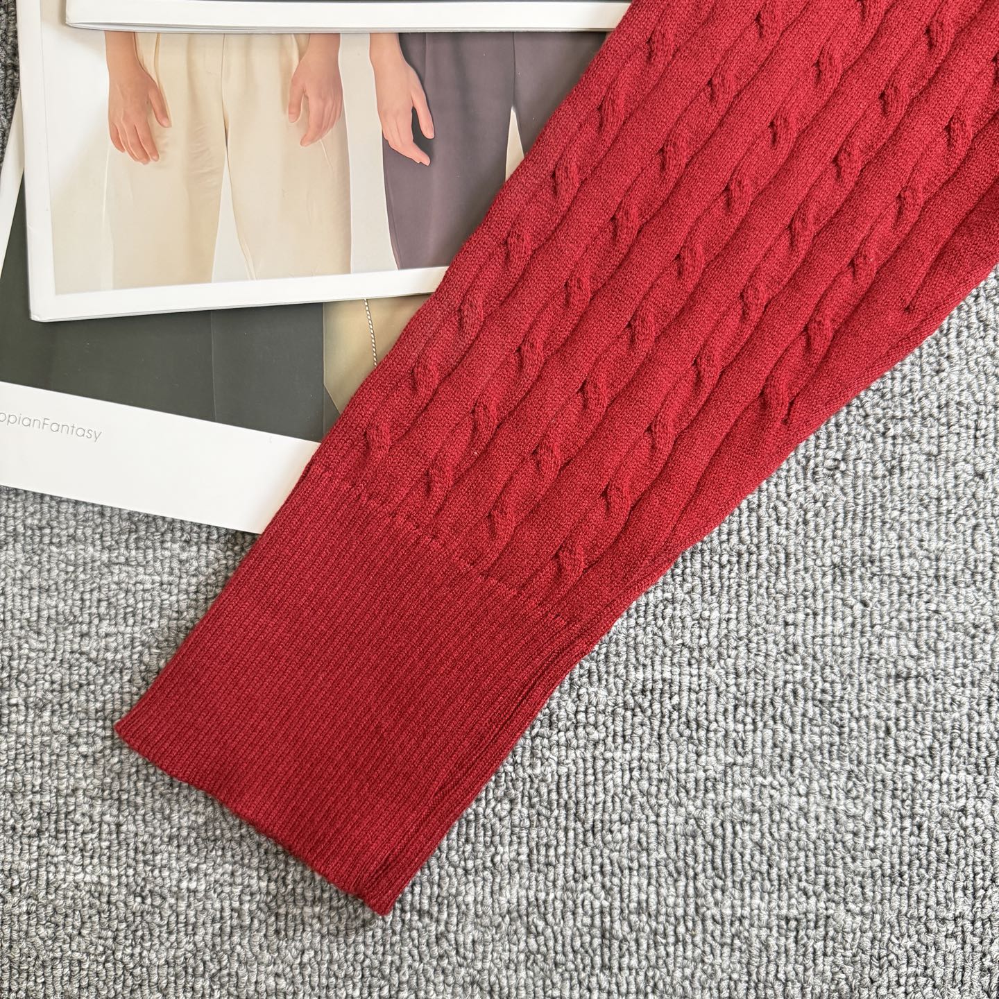 Red cable-knit cardigan sleeve and ribbed cuff with textured knit pattern