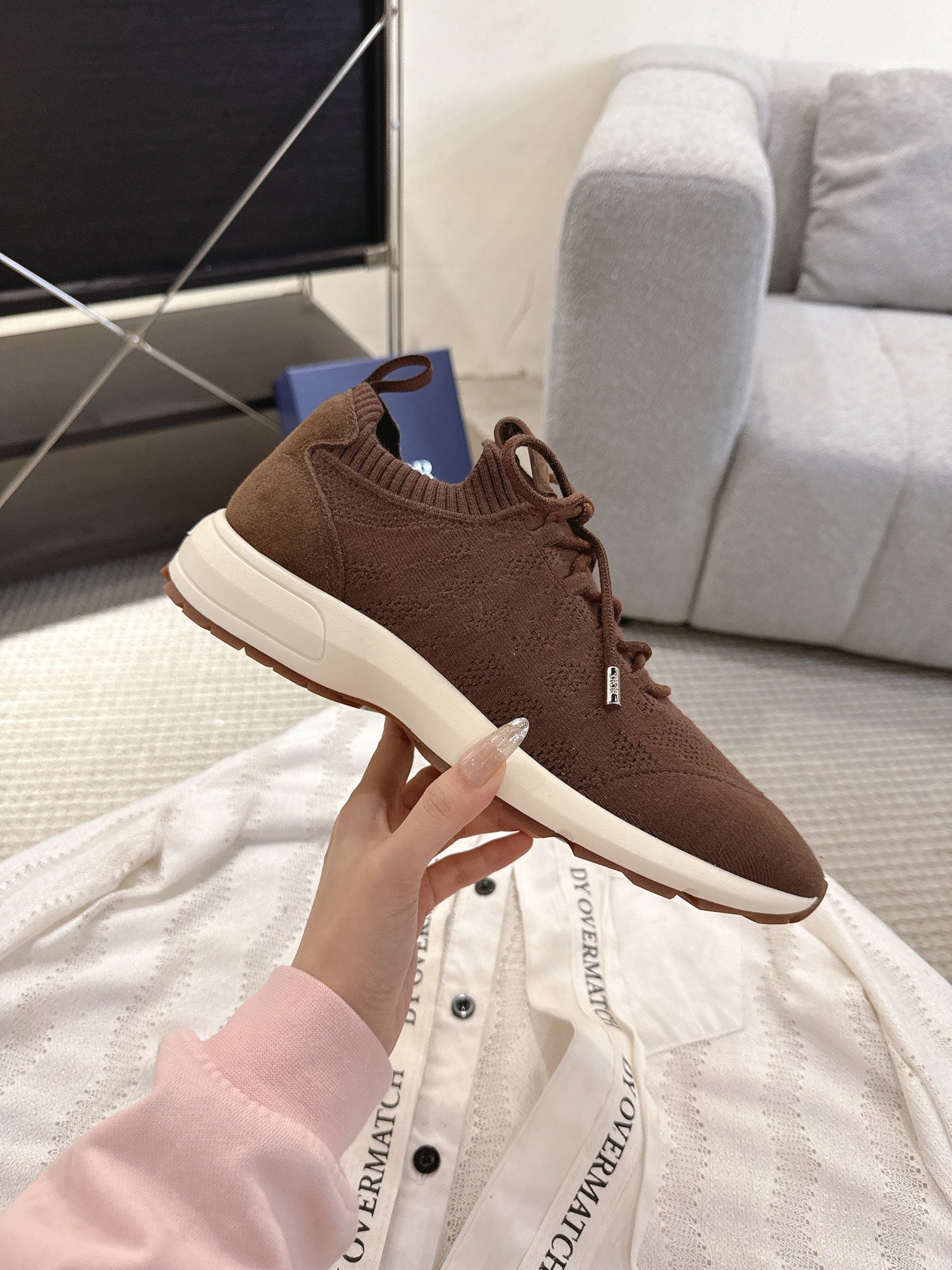 Dior unisex brown sneakers being held, lace-up knit upper with white sidewall sole