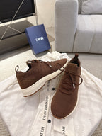 Dior unisex brown sneakers on a white fabric backdrop, lace-up with white soles