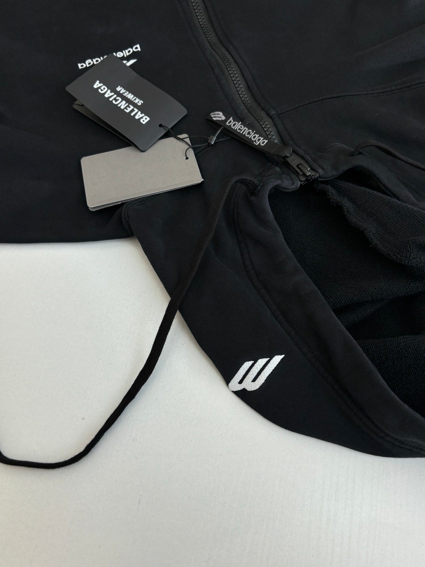 Balenciaga black hoodie front close-up with zipper, hood cord, and tag