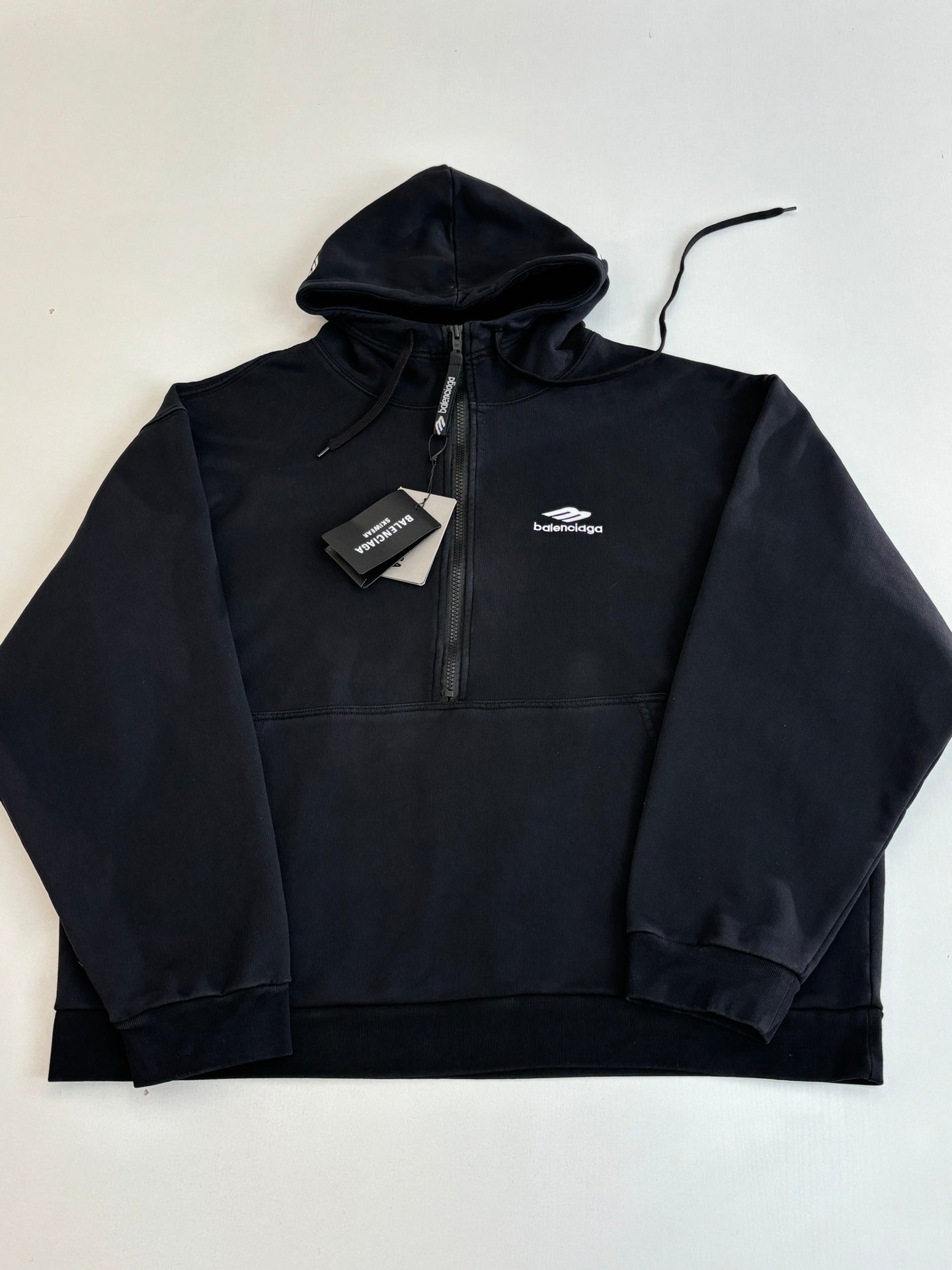 Balenciaga black zip-up hoodie laid flat with hood and chest logo