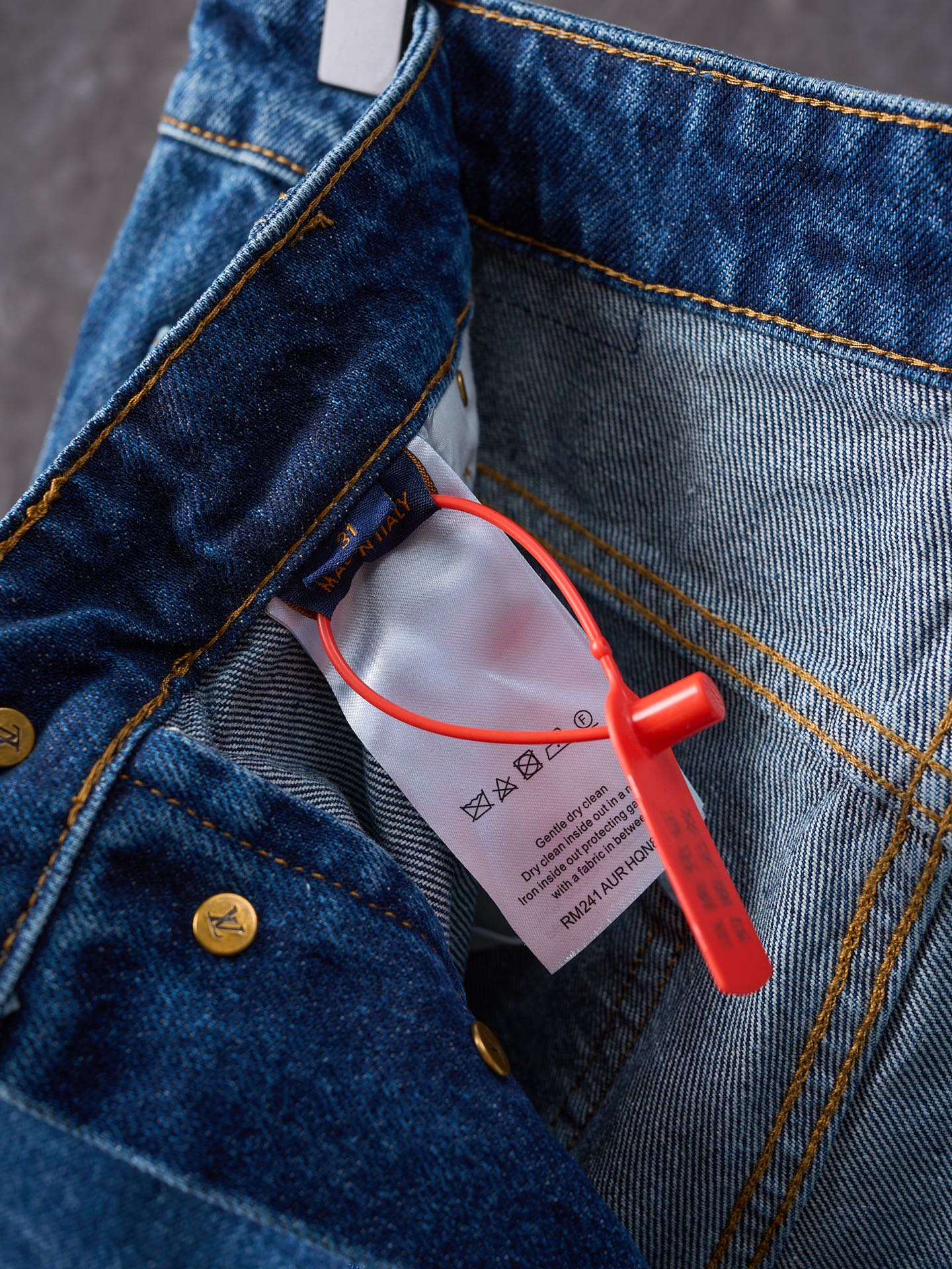 Louis Vuitton blue denim pants close-up of pocket edge and red security tag