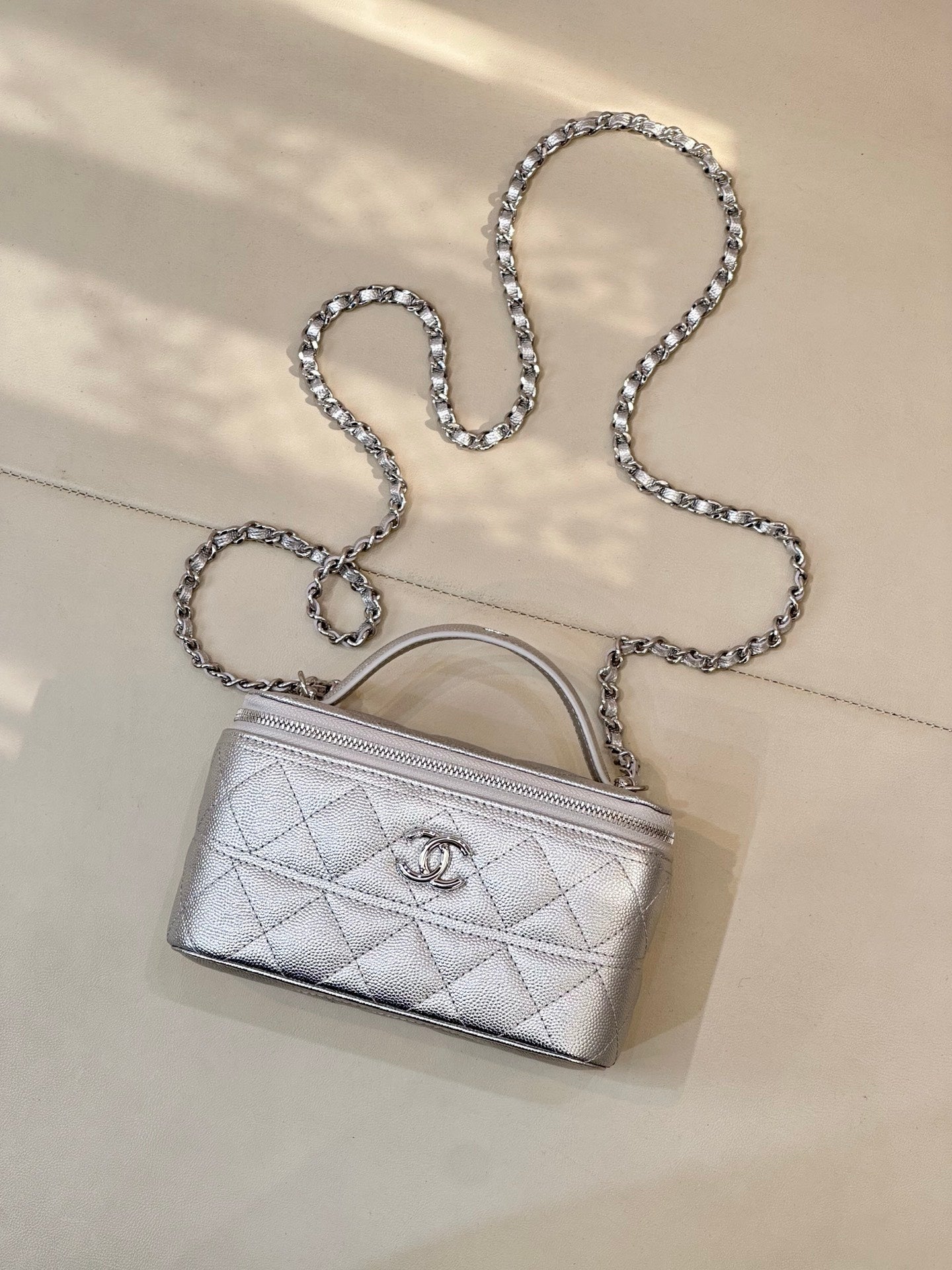 Quilted mini handbag with silver-tone chain shoulder strap and top handle, front logo emblem