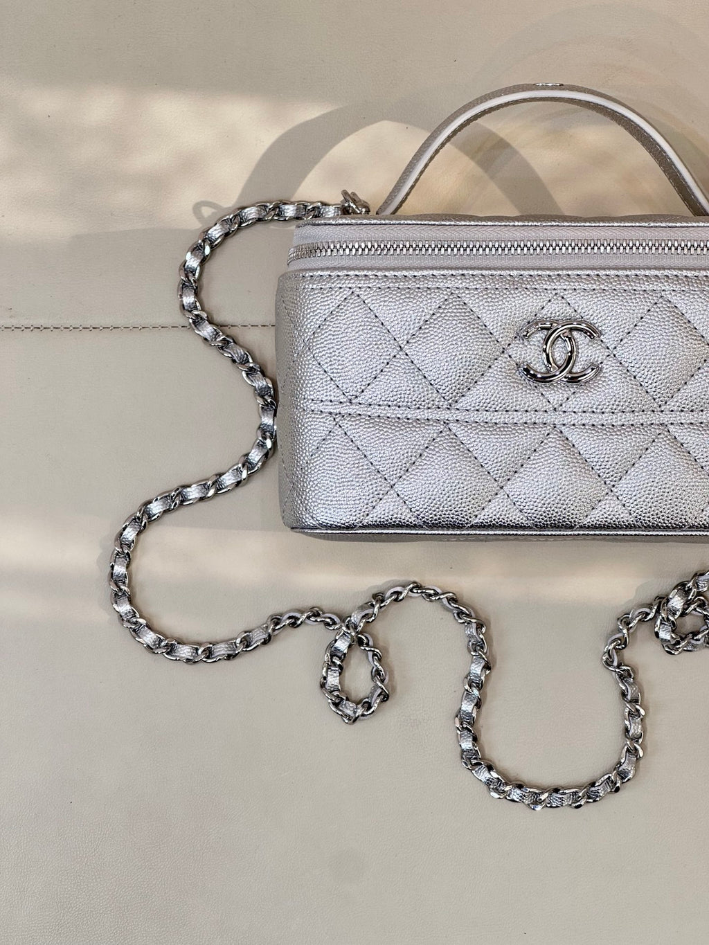 Quilted mini handbag close-up with silver-tone chain strap and front logo emblem, zip top