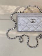 Quilted mini handbag close-up with silver-tone chain strap and front logo emblem, zip top