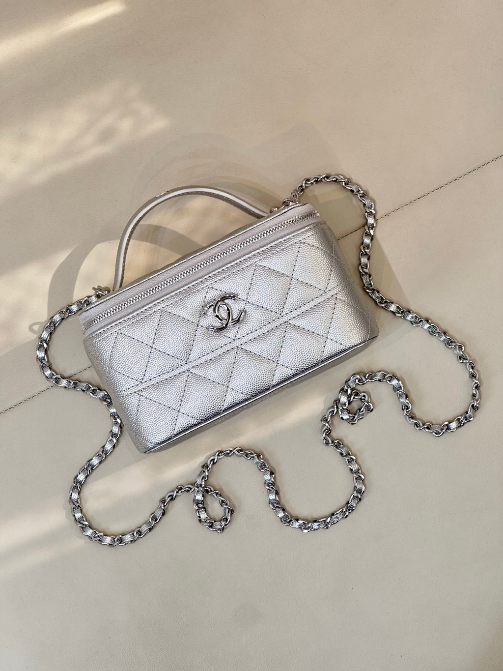 Quilted mini handbag in light silver with top handle and chain strap, front flap logo
