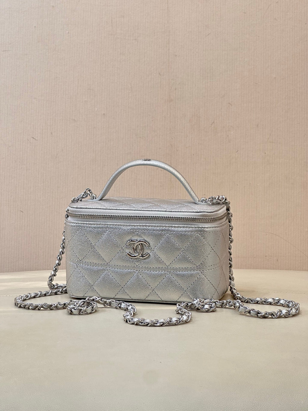Small quilted handbag with top handle and silver-tone chain strap, front logo medallion