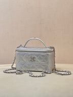 Small quilted handbag with top handle and silver-tone chain strap, front logo medallion