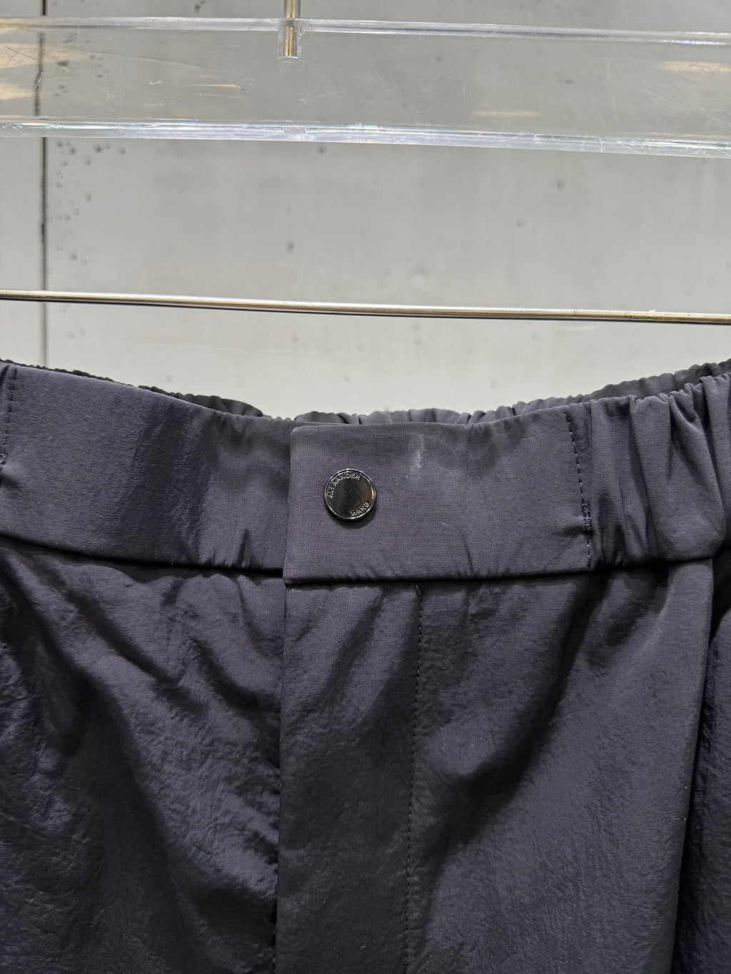 Balenciaga dark pants waistband with metal button at center and elastic gathers