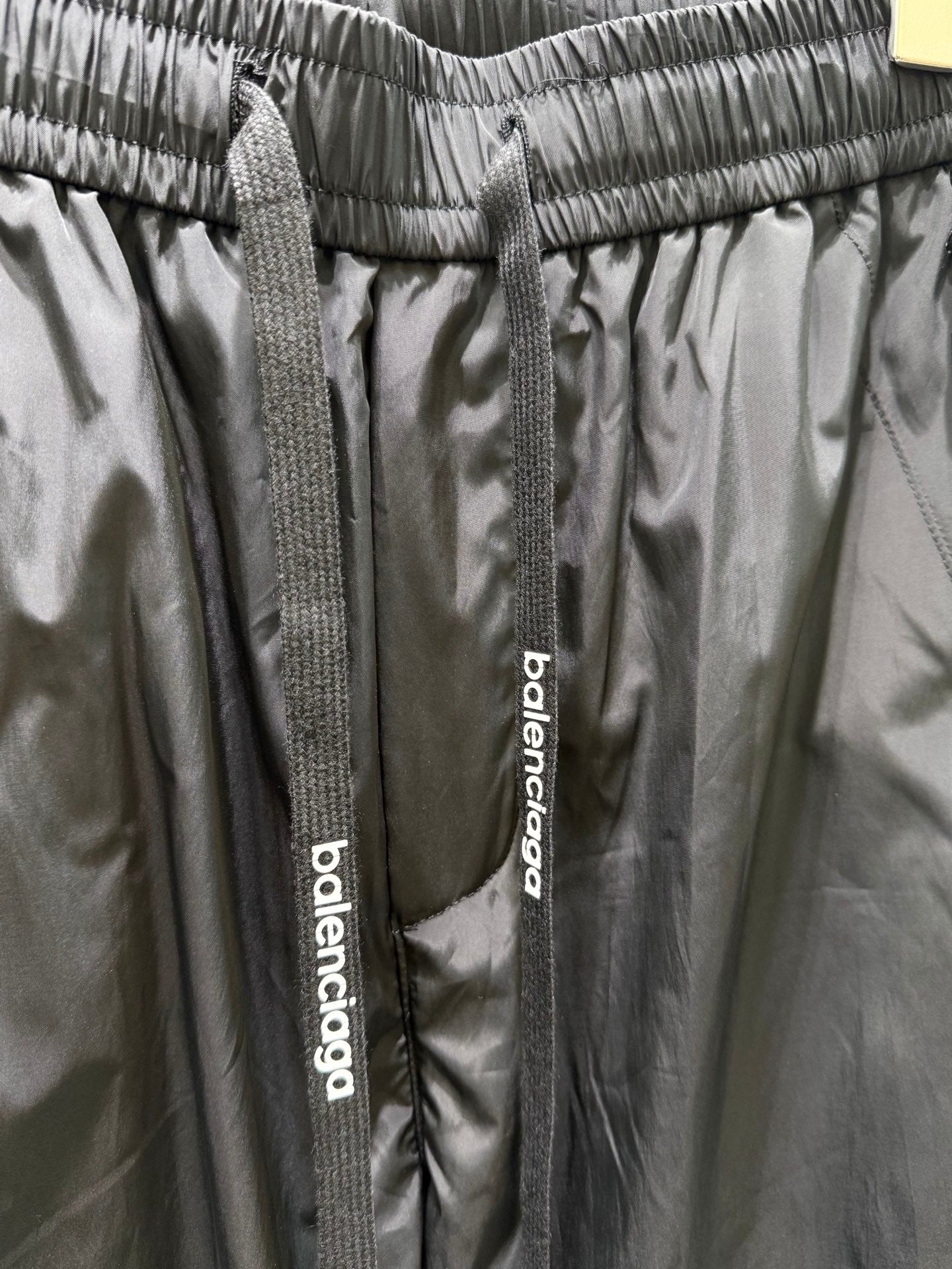 Balenciaga black pants waistband detail with woven drawstring tags and logo label