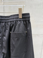 Chrome pants front pocket with button closure, elastic waistband, dark fabric.
