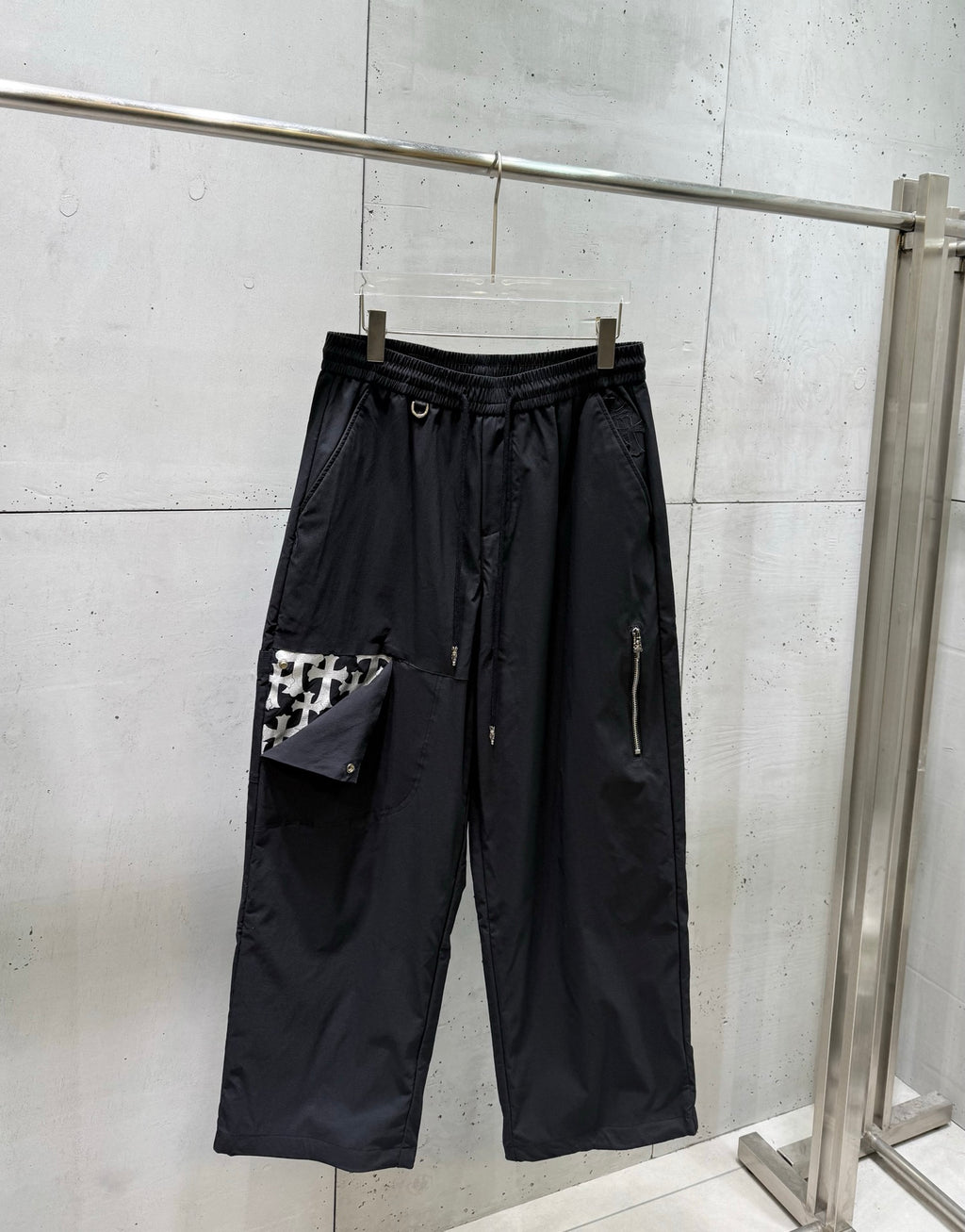 Chrome pants with elastic waist and drawstring, wide straight legs, dark fabric.