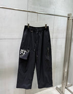 Chrome pants with elastic waist and drawstring, wide straight legs, dark fabric.