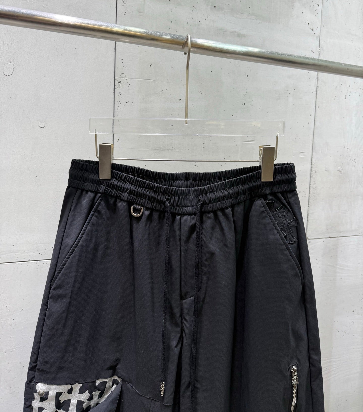 Chrome pants waistband detail with elastic band and drawstring, dark fabric, front seams.
