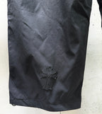 Chrome pants leg with raised cross emblem on dark fabric.