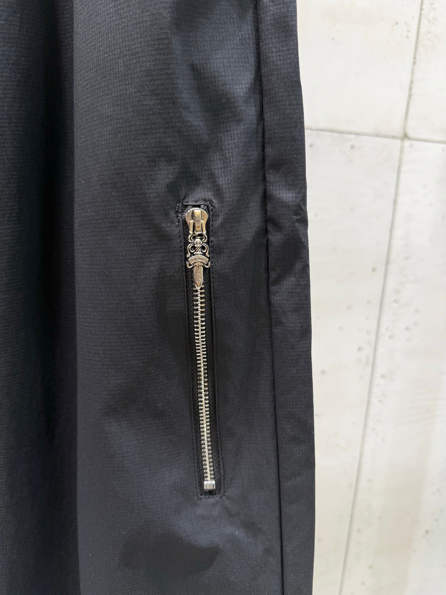 Dark pants with side zipper pocket and gold chain pull
