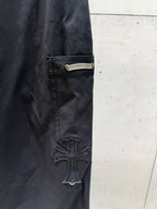 Chrome pants side pocket and raised cross logo patch on dark fabric.