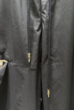 Dark pants with gold zipper fly and small embroidered detail at center seam