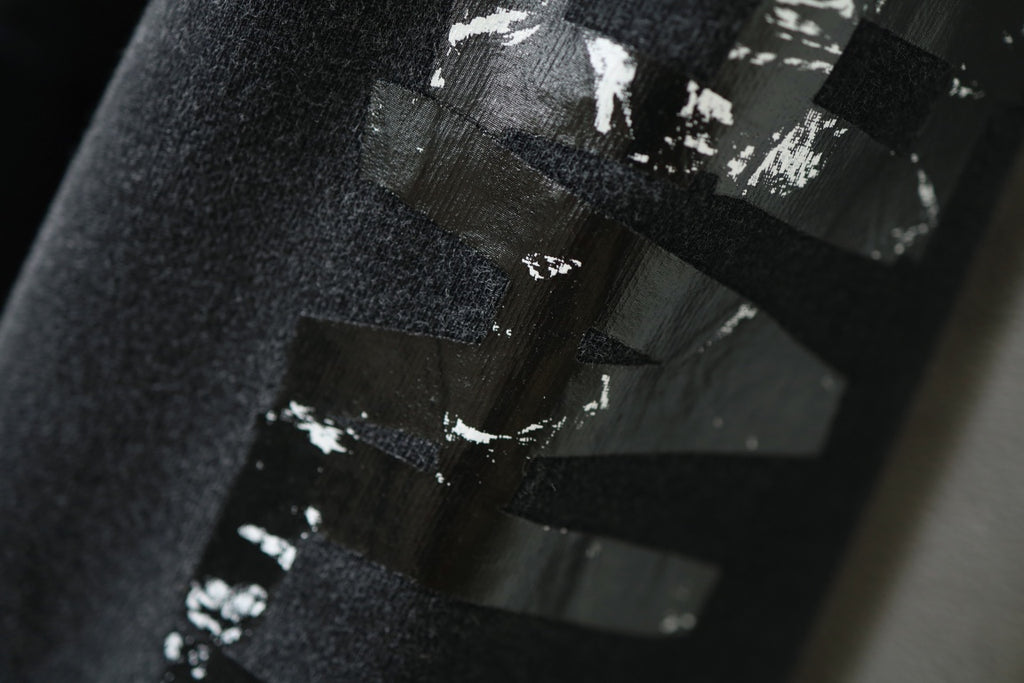 Distressed black-and-white lettering graphic on sweatshirt sleeve.