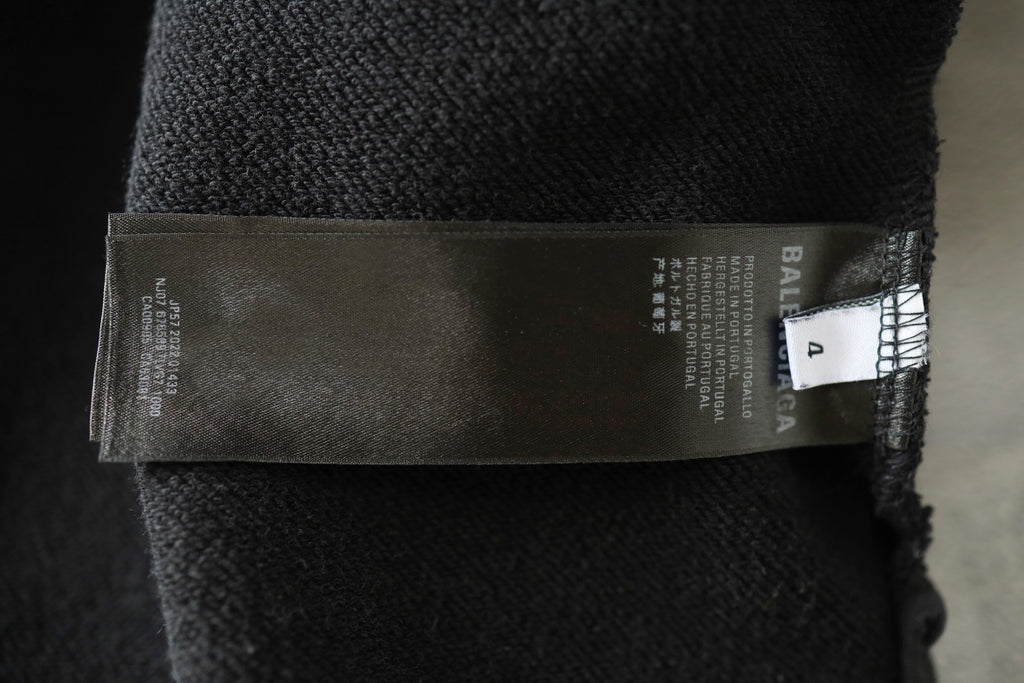 Black fabric label tag inside hooded sweatshirt with printed size text.