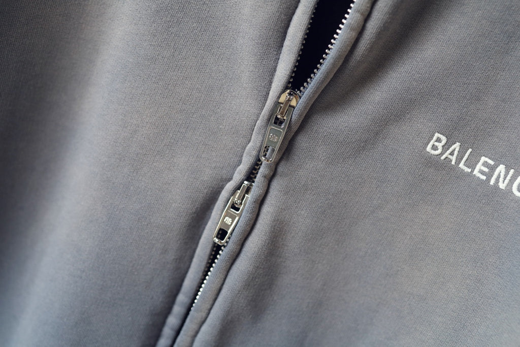 Light gray zip-up sweatshirt detail with metal zipper and BALENCIAGA logo