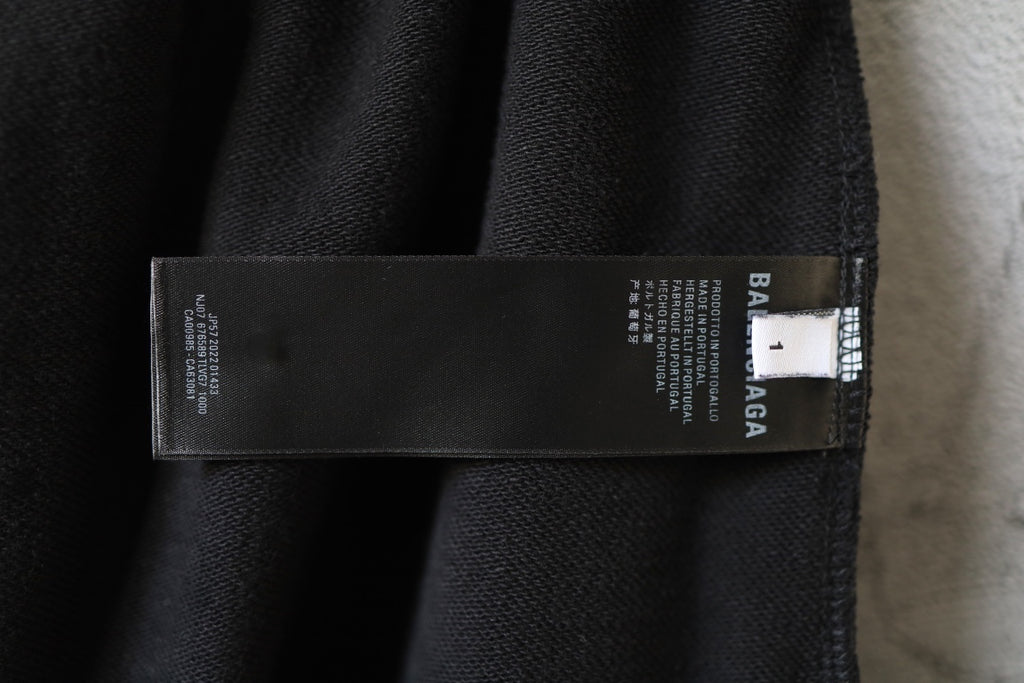 Black fabric pants with printed brand care label sewn inside at waistband