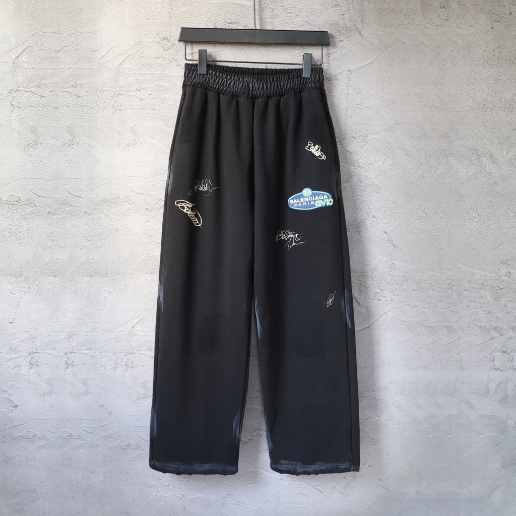 Black wide-leg pants with elastic waistband and small embroidered logo marks on legs