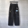 Black wide-leg pants with elastic waistband and small embroidered logo marks on legs