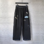 Black wide-leg pants with elastic waistband and small embroidered logo marks on legs