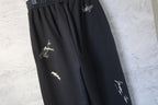 Close-up of black wide-leg pants with embroidered logo marks on the thigh