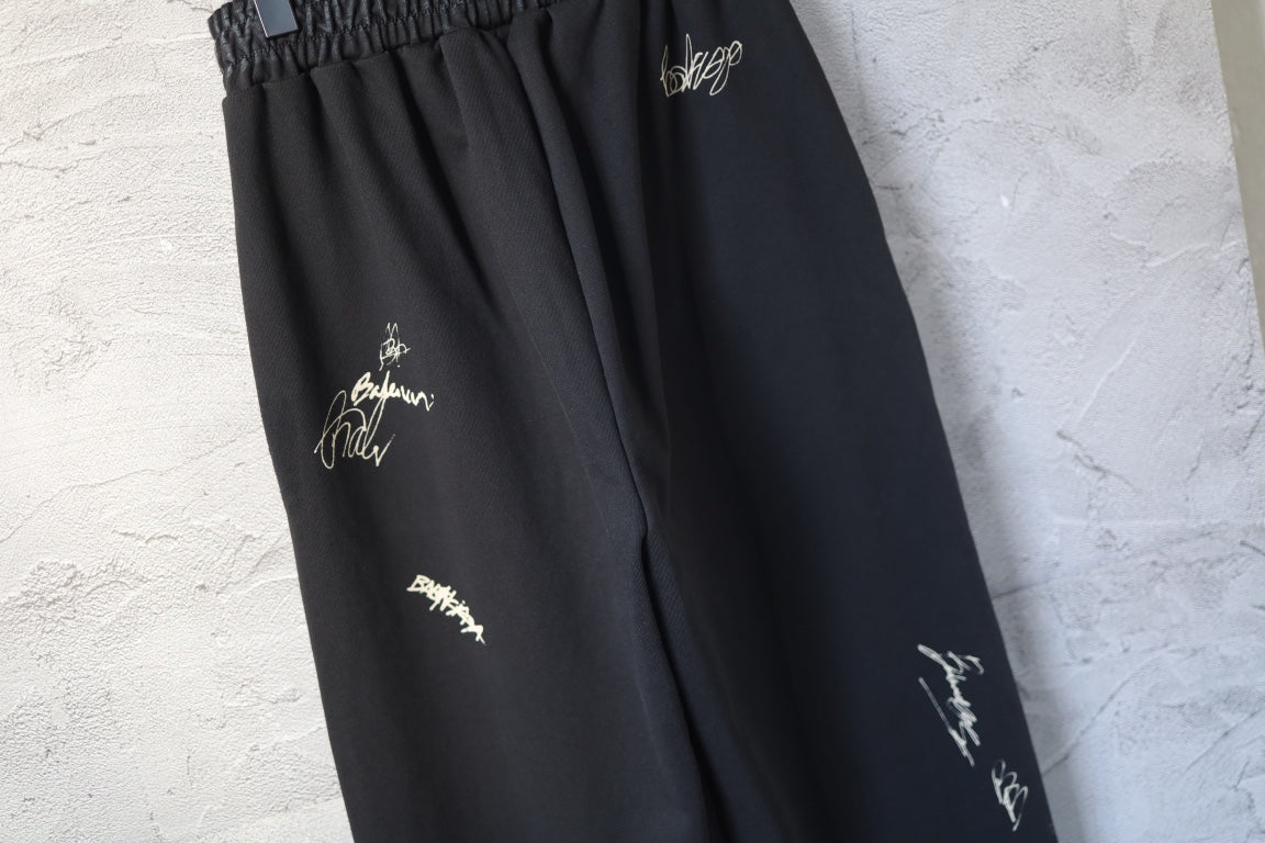 Close-up of black wide-leg pants with embroidered logo marks on the thigh