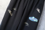 Black wide-leg pants detail with embroidered script and a blue logo patch pocket
