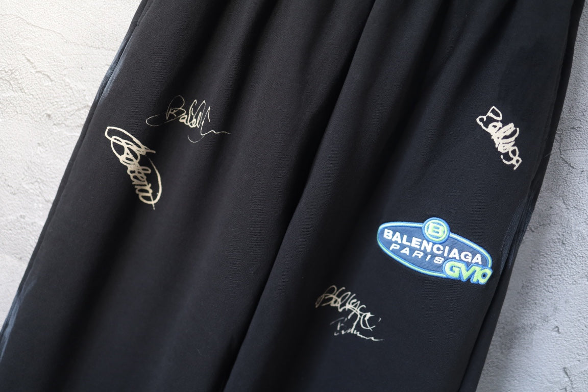 Black wide-leg pants detail with embroidered script and a blue logo patch pocket