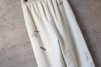 Cream pants with logo print and gathered front fabric detail