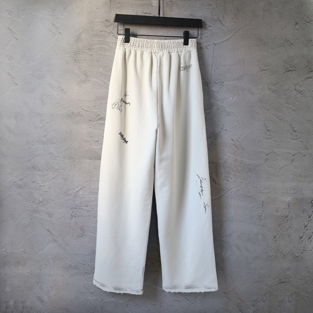 Cream wide-leg pants with elastic waistband and scattered logo graphics