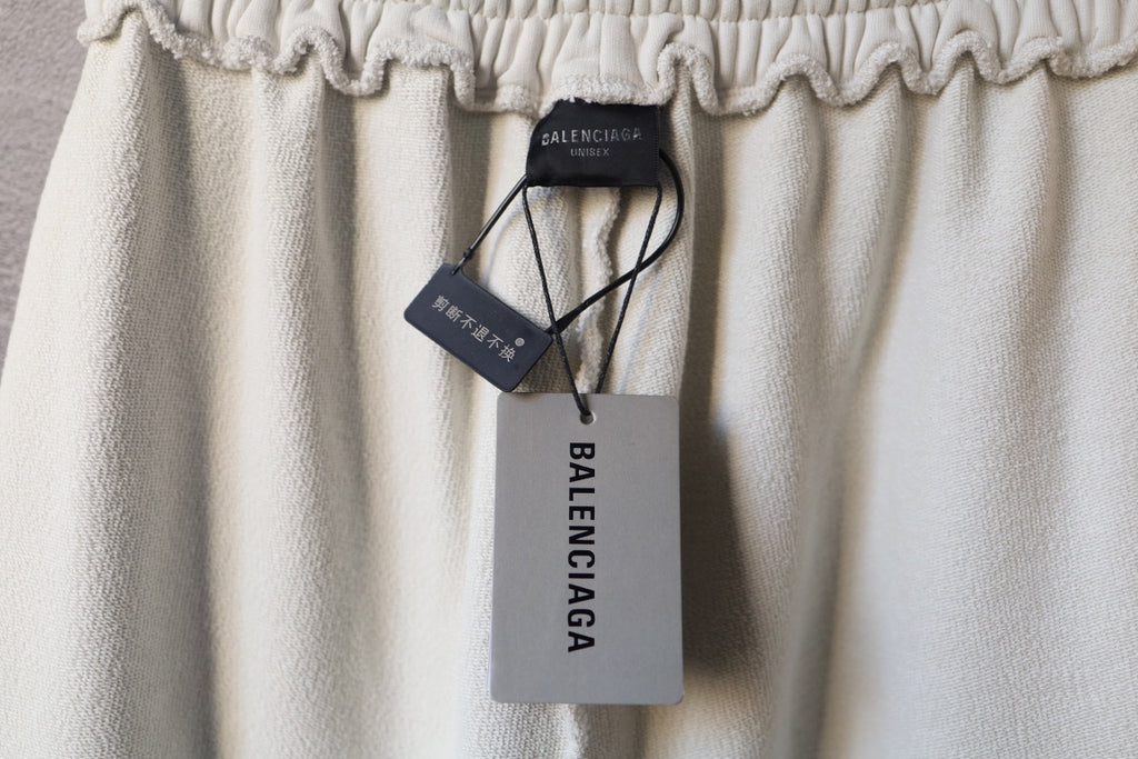 Cream pants with hanging Balenciaga tags and elastic waistband