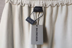 Cream pants with hanging Balenciaga tags and elastic waistband