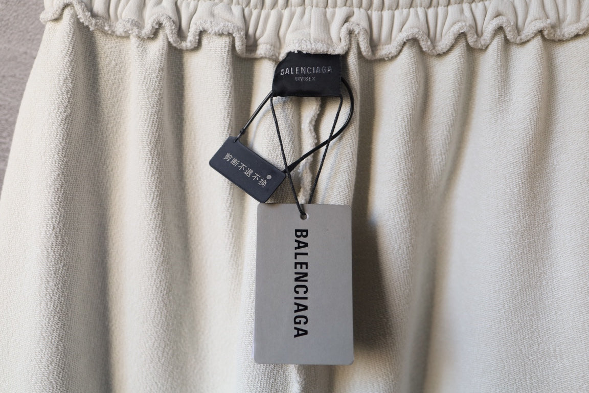 Cream pants with hanging Balenciaga tags and elastic waistband