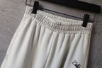 Cream elastic waistband pants with stitched gathers and logo detail