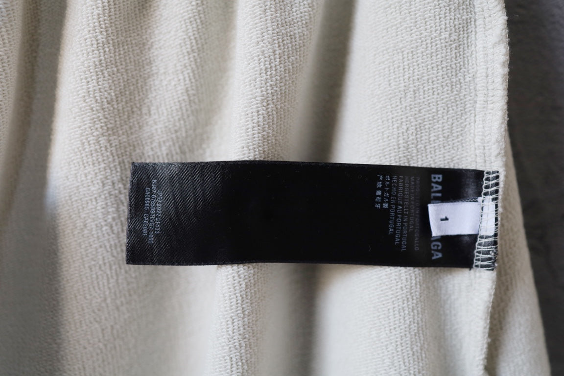 Cream pants showing black size and care label stitched at side seam