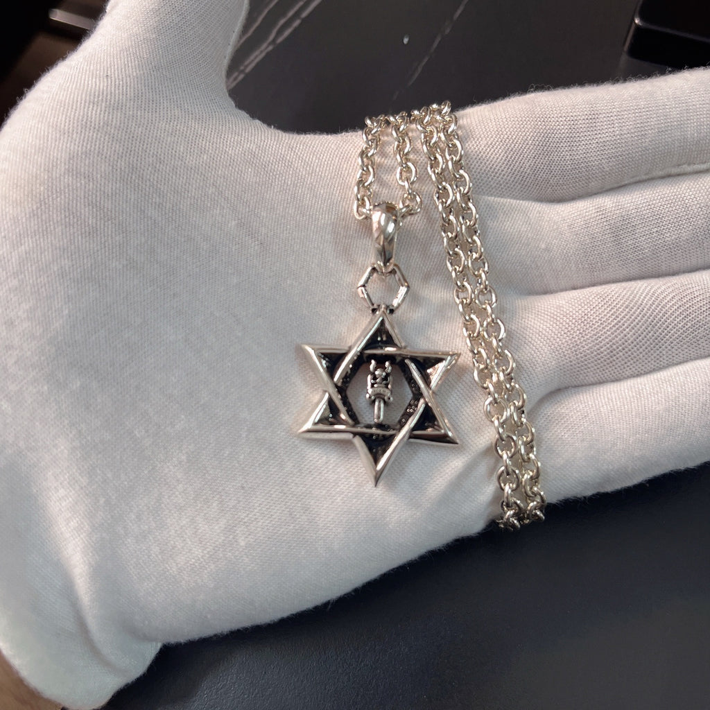 Silver chain necklace with star pendant charm on gloved hand