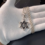 Silver chain necklace with star pendant charm on gloved hand