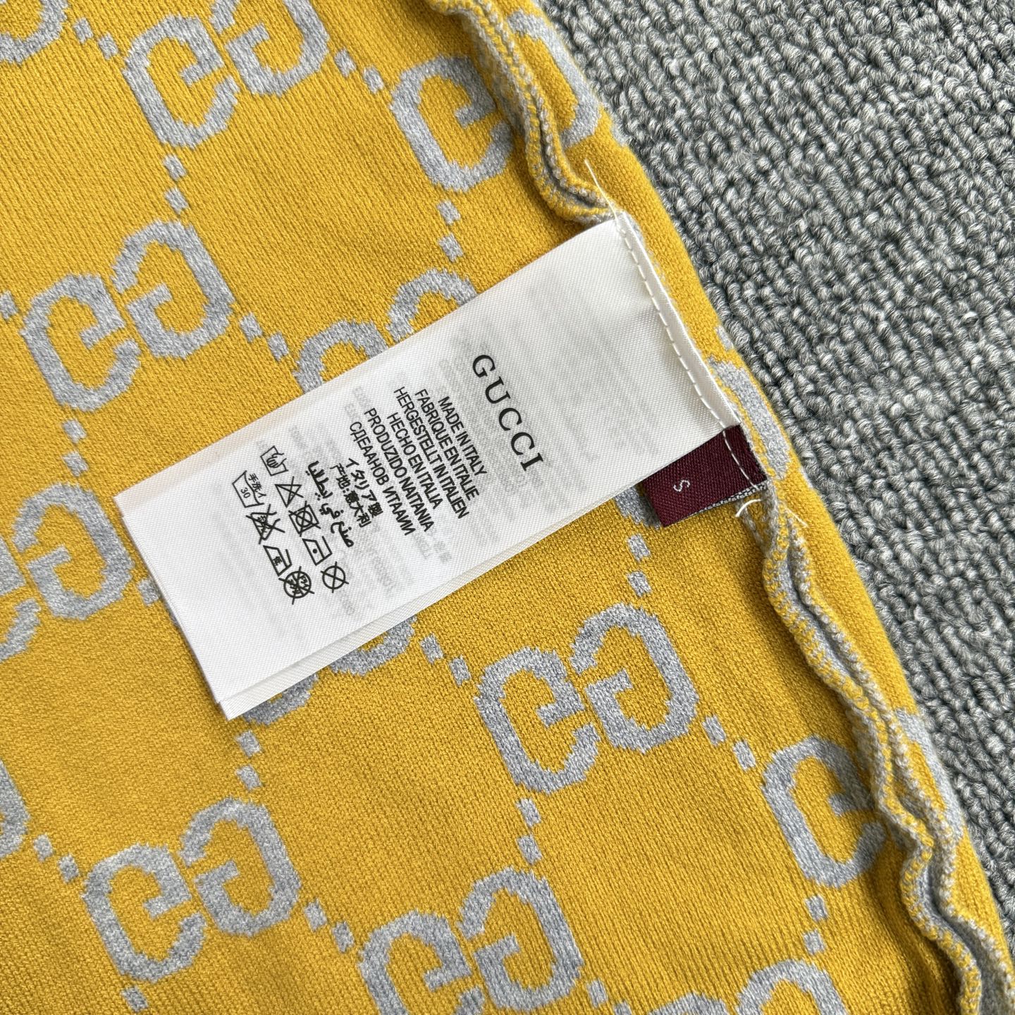 Yellow knit sweater label area with GG logo pattern and stitched neckline