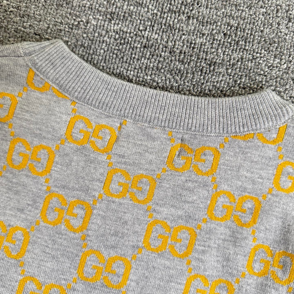 Close-up of sweater upper section with heather gray knit and yellow GG logo pattern