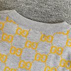 Close-up of sweater upper section with heather gray knit and yellow GG logo pattern