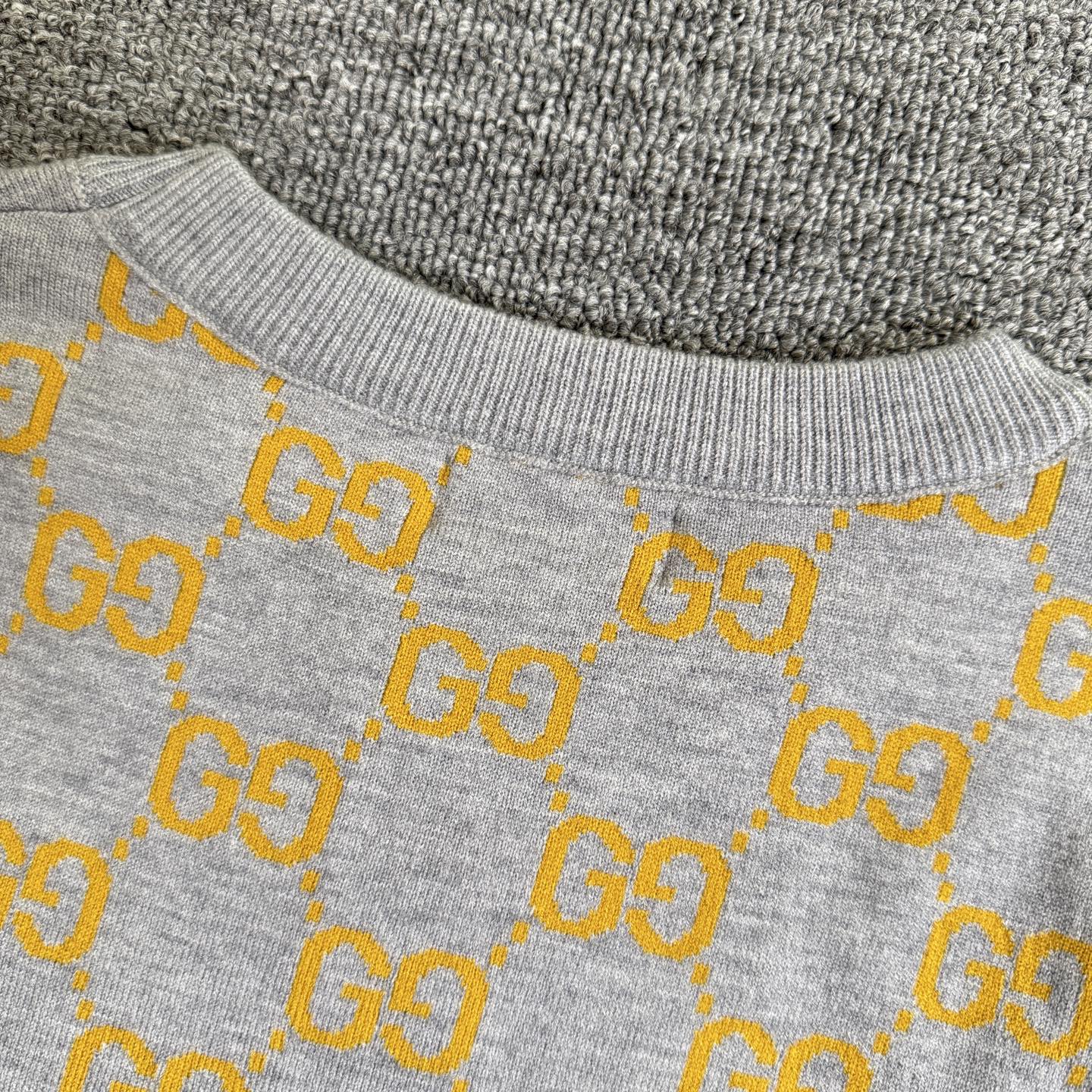 Close-up of sweater upper section with heather gray knit and yellow GG logo pattern
