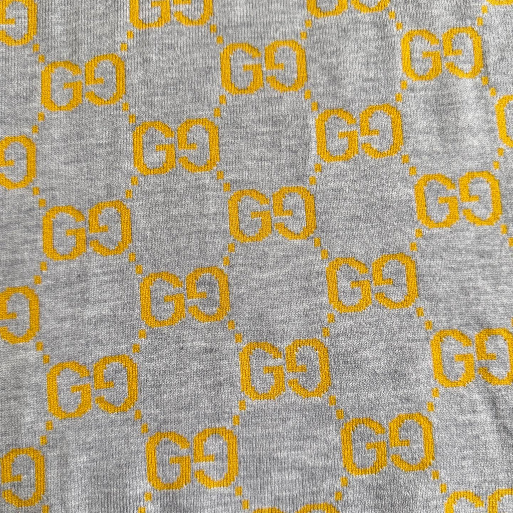 Close-up of heather gray knit fabric with repeating yellow GG logo pattern