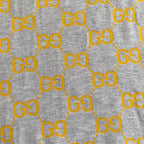Close-up of heather gray knit fabric with repeating yellow GG logo pattern